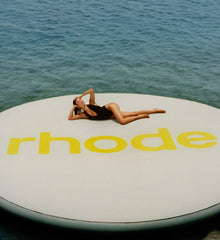 HB lying down on a giant float with rhode logo