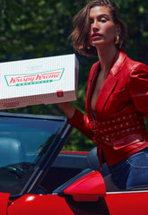 Hailey Bieber with glossy lips, holding a box of Krispy Kreme Doughnuts
