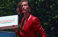 Hailey Bieber with glossy lips, holding a box of Krispy Kreme Doughnuts