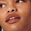 Model wears Peptide Lip Tint in shade Toast