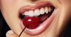 close up of model wearing peptide lip treatment with glossy lips, biting into a cherry