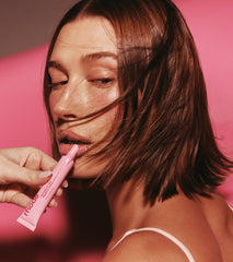 Hailey Bieber with peptide lip tint in jelly bean being applied on lips