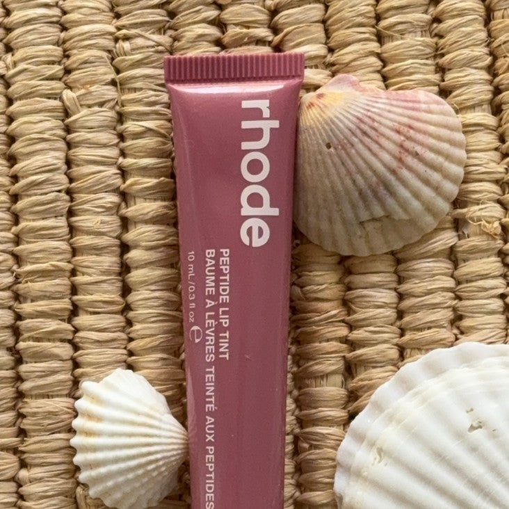 peptide lip tint salty tan next to shells