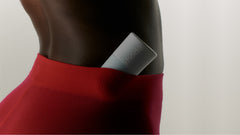 A close up of a model wearing red stockings, with a Peptide Glazing Fluid nestled into the waistband