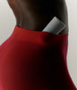 A close up of a model wearing red stockings, with a Peptide Glazing Fluid nested into the waistband
