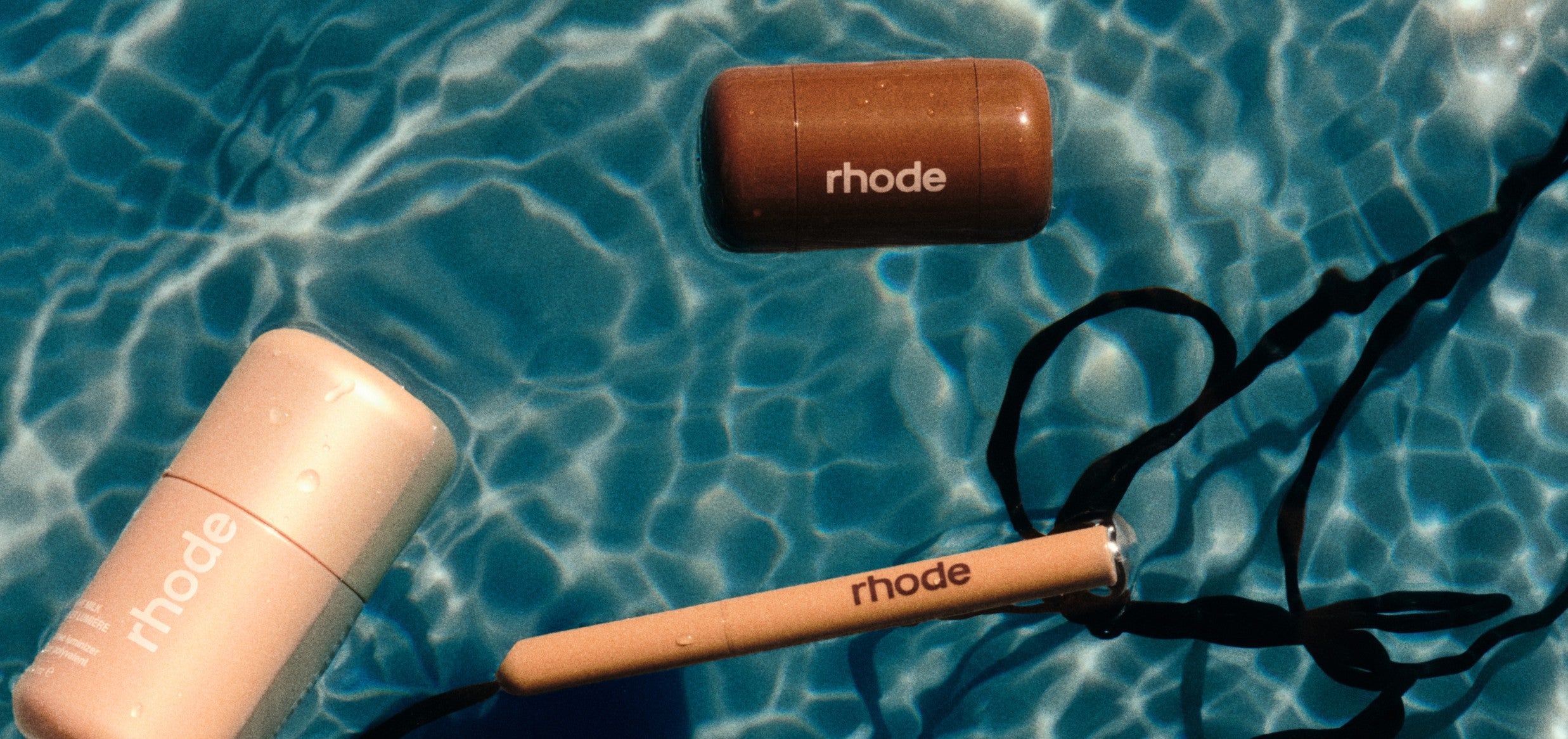 Collection of rhode skincare products on a dark surface