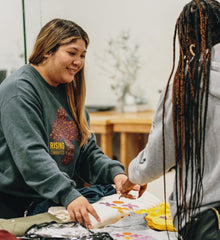 Two people engaging in a craft activity together, with one person smiling and the other interacting.