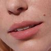 Model wears Peptide Lip Tint in shade Ribbon