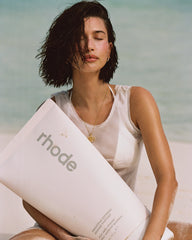 Hailey Bieber on the beach, holding a mega-sized pineapple refresh bottle