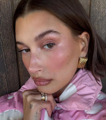 Hailey Bieber with glossy, shimmery lips, wearing peptide lip tint in jelly bean