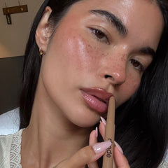 Woman applying peptide lip shape with a focus on her lips and the product.