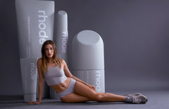 Hailey Bieber in front of life size rhode collection