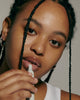 model with glazed skin, applying peptide lip treatment (unscented)