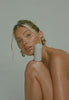 Model balancing peptide glazing fluid on leg, glowing skin